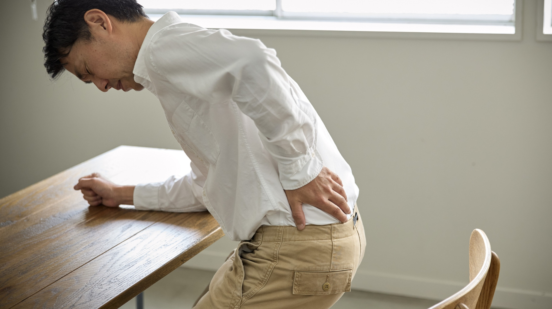 Man suffering from chronic pain due to poor posture. The link between poor posture and back pain.